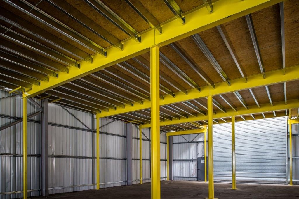 Underside of a mezzanine floor showing steel beams, columns and decking.